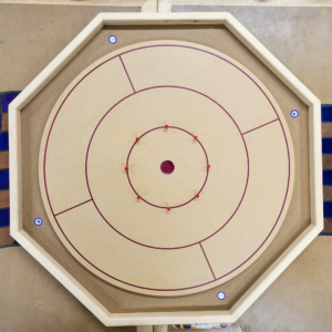Handcrafted octagonal Crokinole board with a smooth wooden surface, red scoring pegs, and marked play zones, perfect for family and social gaming