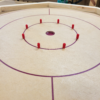 crokinole Handcrafted octagonal Crokinole board with a smooth wooden surface, red scoring pegs, and marked play zones, perfect for family and social gaming