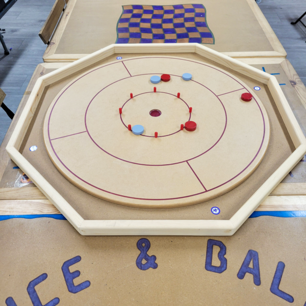 crokinole Handcrafted octagonal Crokinole board with a smooth wooden surface, red scoring pegs, and marked play zones, perfect for family and social gaming