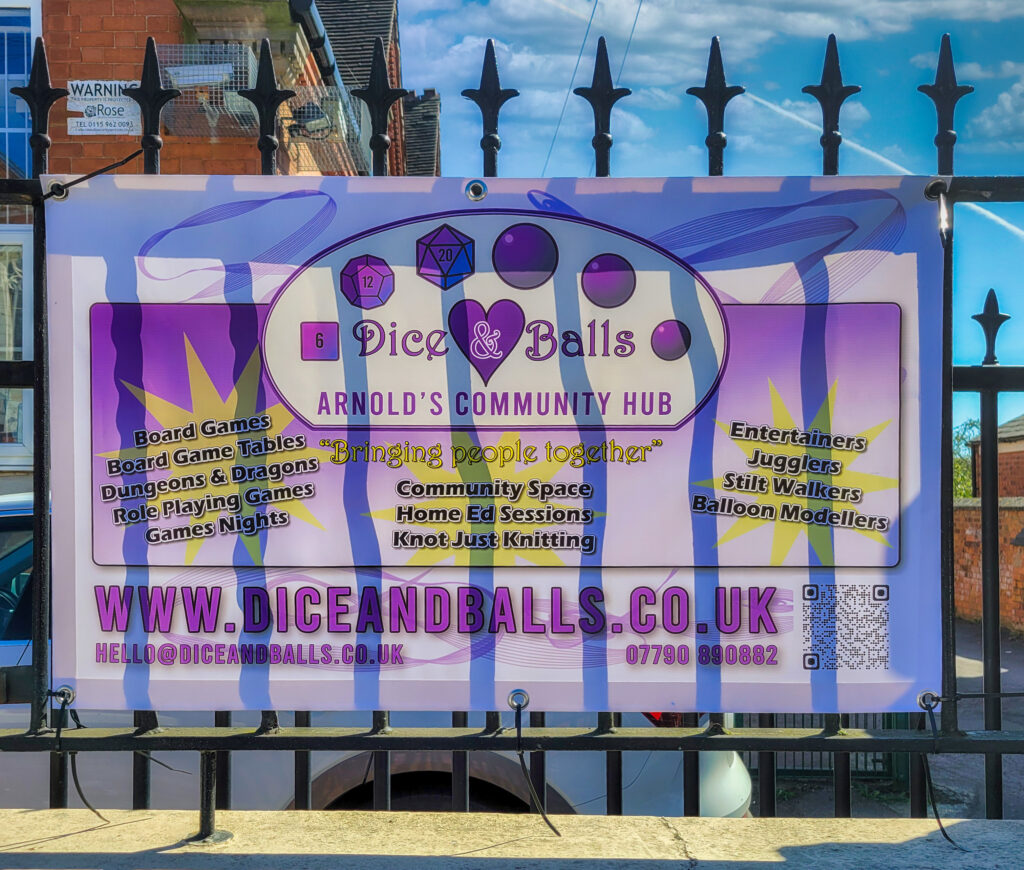 Dice and Balls CIC community banner displayed on railings outside Studio 8, The Old School Business Centre in Arnold, Nottingham, promoting board games, Dungeons & Dragons, knitting groups, circus skills, and community events.